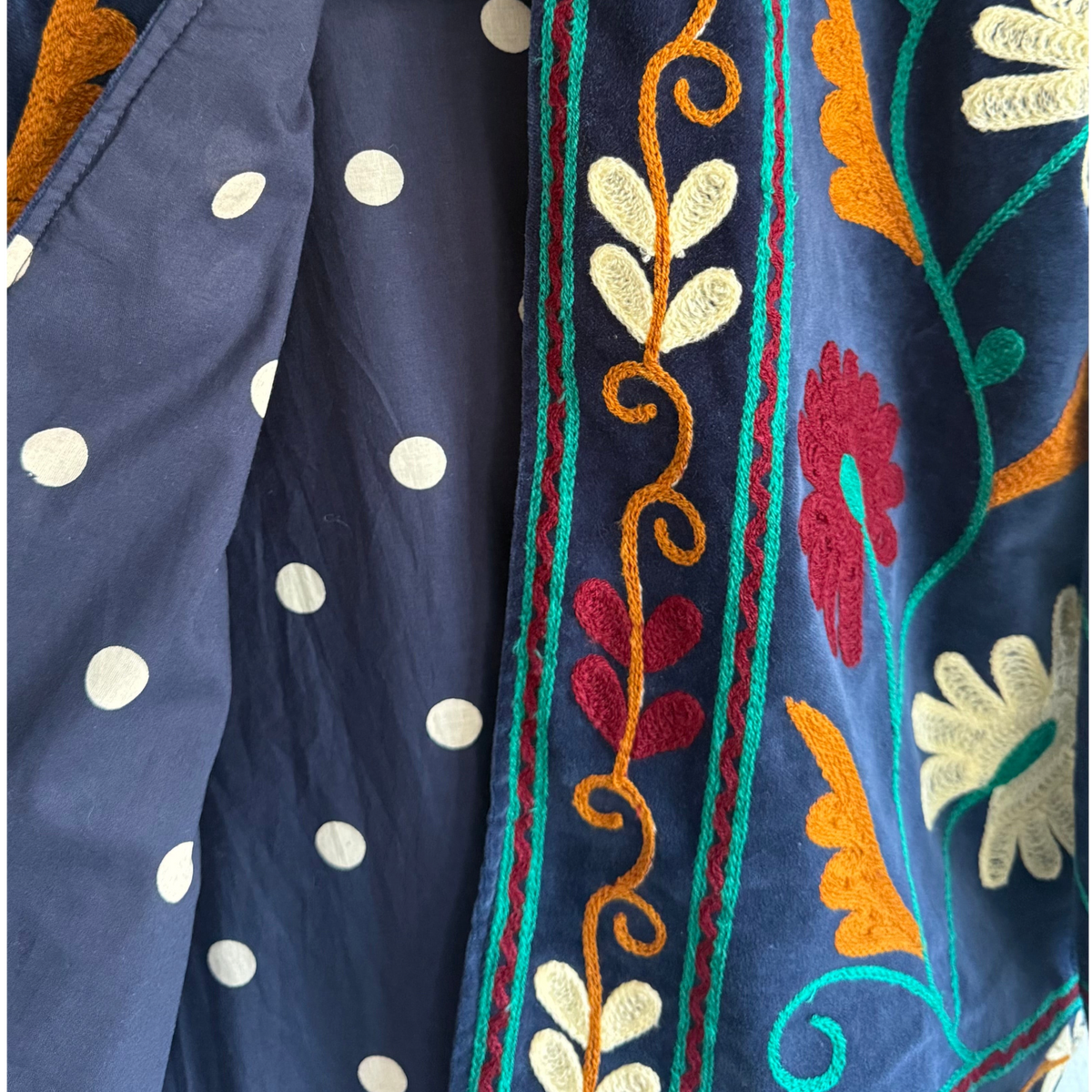 Casaco Grine de veludo azul com bordados florais coloridos e interior reversível em algodão com padrão de bolas.