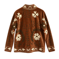 Casaco Grine de veludo camel com bordados florais estilo Suzani, gola subida e detalhes botânicos em tons claros.