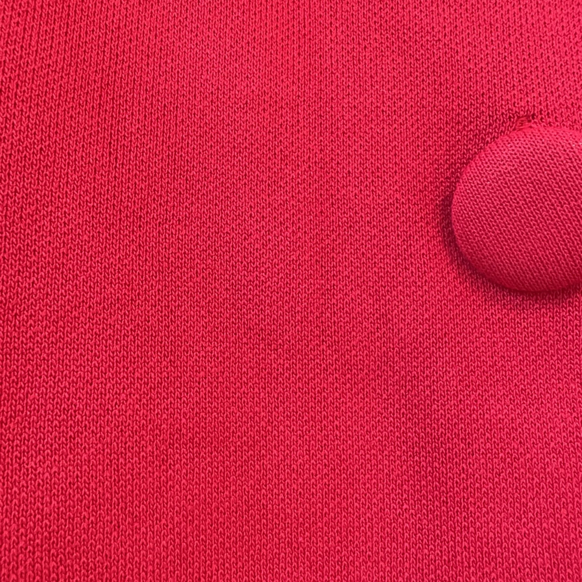 Detalhe do tecido vermelho em viscose do casaco GRINE com botão forrado no mesmo tom