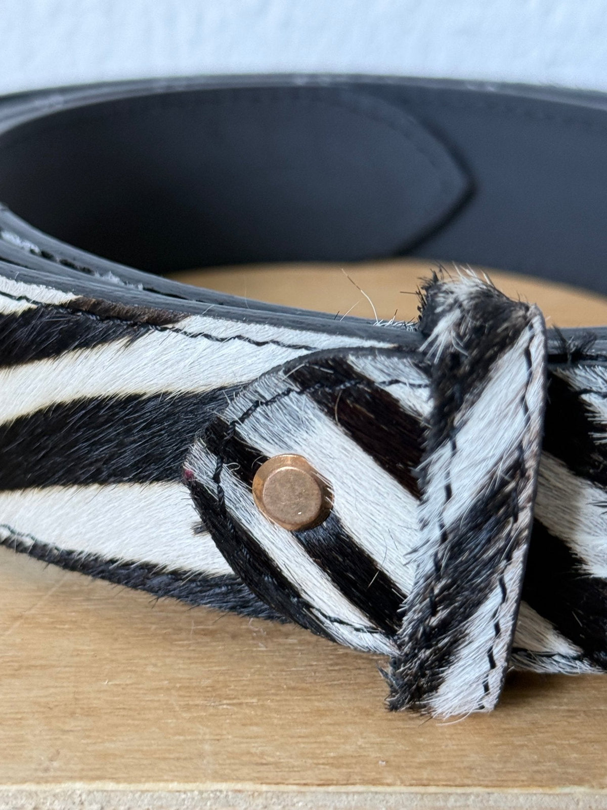 Cinto GRINE de couro com padrão de pelo de zebra em preto e branco, detalhe de rebite metálico e 3,5 cm de largura.