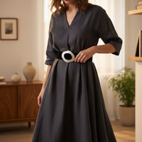 Cinto largo de camurça preto GRINE com fivela grande, usado por mulher com vestido cinzento em ambiente elegante.