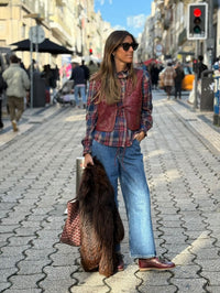 Mulher usa colete GRINE Chester em PU bordeaux com tachas e bordados, sobre camisa xadrez e calças de ganga largas.