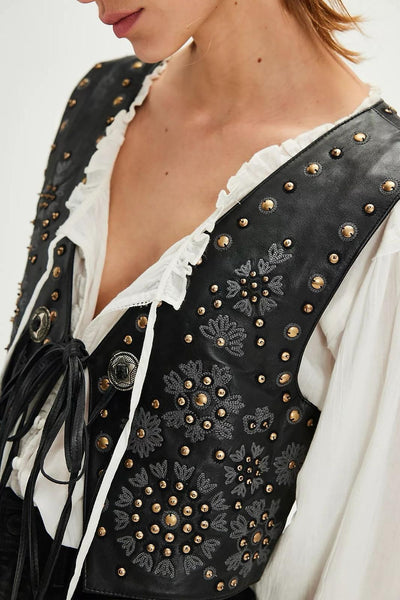 Colete GRINE Chester em PU preto com bordados florais e tachas metálicas, fechado com atilho frontal.