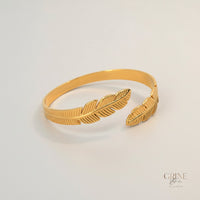 GRINE gold-tone stainless steel cuff bracelet with delicate leaf design. Adjustable and hypoallergenic.