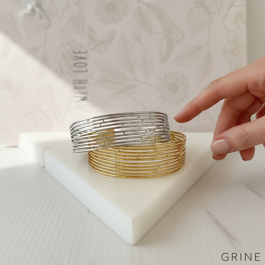 GRINE stackable stainless steel bangles in gold and silver tones. Adjustable, water-resistant, and hypoallergenic.