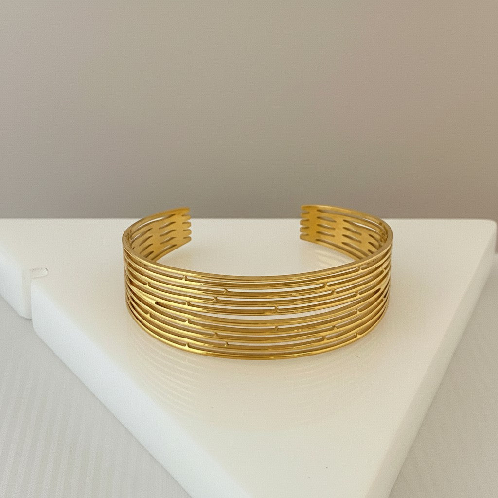 GRINE gold-tone stainless steel cuff bracelet with a multi-layered openwork design. Adjustable and water-resistant.