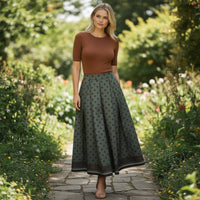 GRINE green polka dot midi skirt with elastic waist and pleated detail, worn by a model in a garden setting.