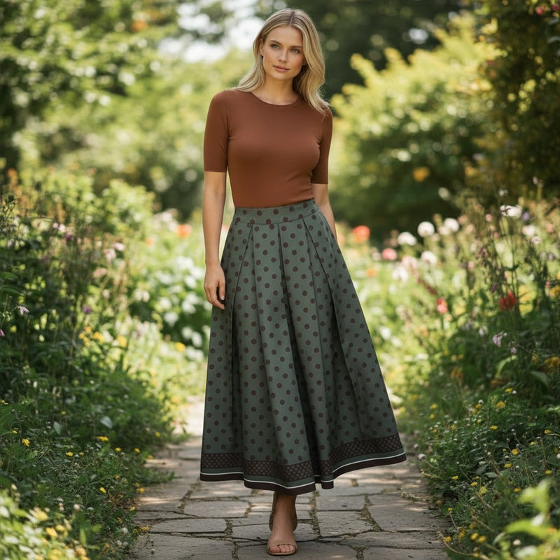 GRINE green polka dot midi skirt with elastic waist and pleated detail, worn by a model in a garden setting.