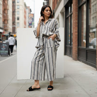 GRINE grey wide-leg trousers with elastic waist, side pockets, and vertical stripe pattern. Made from a rayon, polyester, and cotton blend.