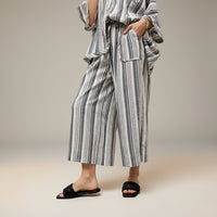 GRINE grey wide-leg trousers with elasticated waist, side pockets, and vertical stripe pattern. Made from a rayon, polyester, and cotton blend.