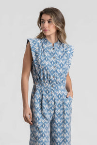 Modelo veste jardineiras azuis GRINE com padrão ikat, corte direito, gola subida e bolsos laterais.