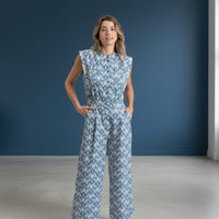 Modelo veste jardineiras azuis GRINE com padrão geométrico, corte direito, sem mangas e bolsos laterais.