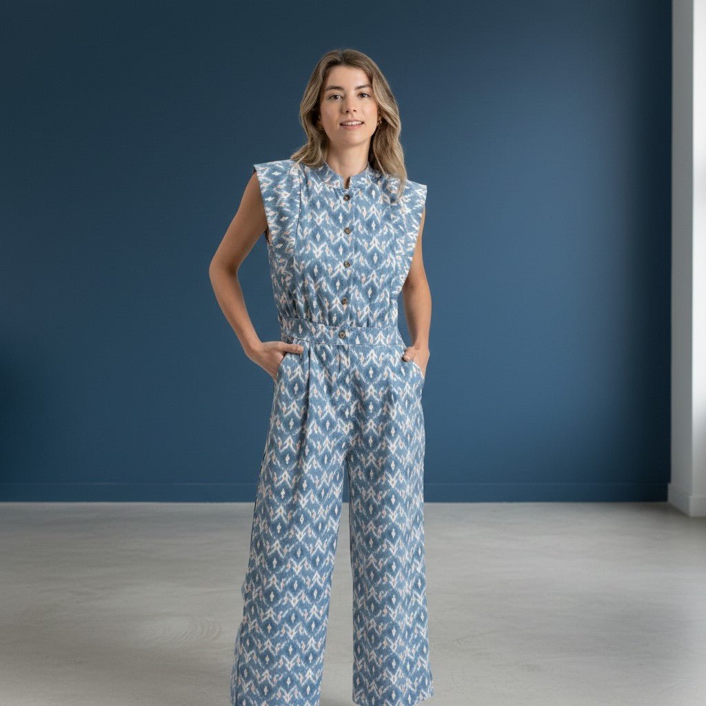 Modelo veste jardineiras azuis GRINE com padrão geométrico, corte direito, sem mangas e bolsos laterais.