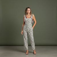 Jardineiras GRINE verdes com padrão floral, corte direito, alças com folhos e bolsos laterais em modelo feminino.