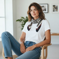Mulher a usar lenço quadrado acetinado GRINE com padrão animal print em tons de preto e bege ao pescoço
