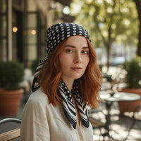 Mulher ruiva usa lenço quadrado GRINE acetinado preto com padrão de bolas brancas amarrado na cabeça ao ar livre