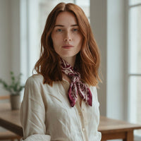 Modelo com lenço quadrado acetinado GRINE na cor bordeaux com padrão paisley atado ao pescoço sobre camisa bege