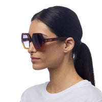 Modelo usa óculos de sol GRINE OKKIA EMMA com armação havana yellow em acetato e lentes pretas polarizadas