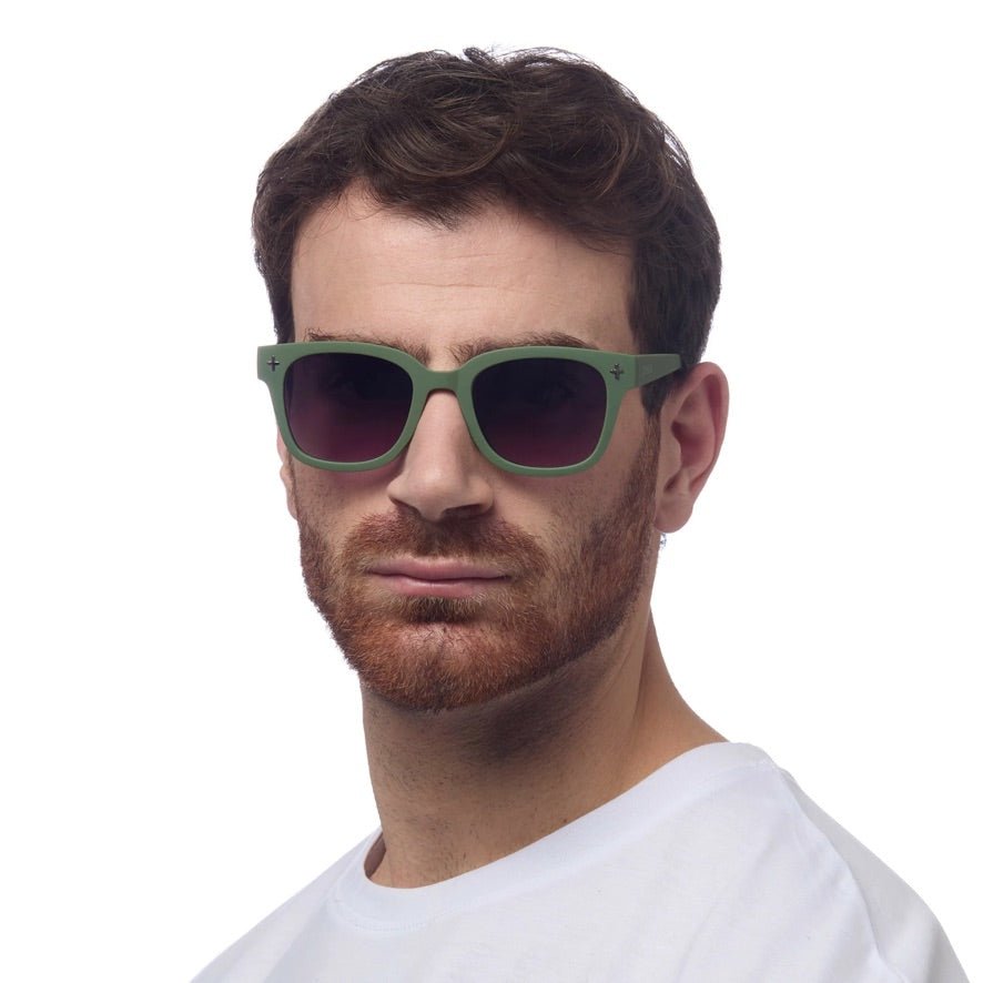 Homem a usar óculos de sol GRINE OKKIA Giovanni com armação verde e preta em acetato e lentes polarizadas pretas