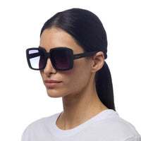 Modelo usando óculos de sol GRINE OKKIA Alessia com armação preta em acetato e lentes degradé polarizadas