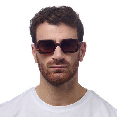 Homem a usar óculos de sol GRINE OKKIA ANDREA com armação em acetato castanho havana e lentes degradé polarizadas.