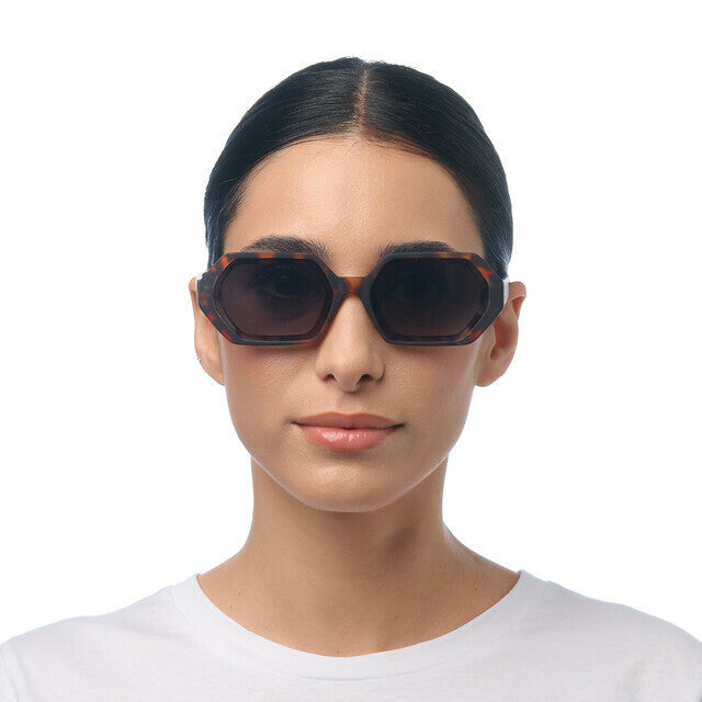 Modelo a usar óculos de sol OKKIA ANDREA com armação hexagonal padrão Havana e lentes verdes degradé