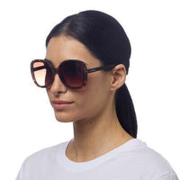 Modelo a usar óculos de sol GRINE OKKIA ANNA com armação em padrão tartaruga Classic Havana e lentes degradé
