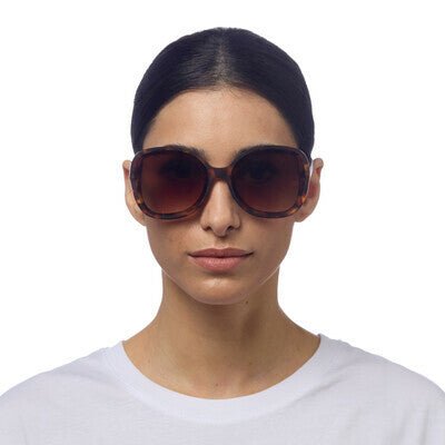 Modelo usa óculos de sol GRINE OKKIA ANNA com armação Classic Havana em acetato e lentes castanhas degradé polarizadas.