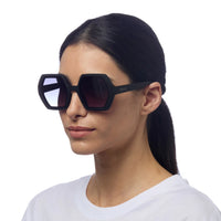 Modelo usa óculos de sol GRINE OKKIA EMMA pretos com armação geométrica em acetato e lentes polarizadas UV400