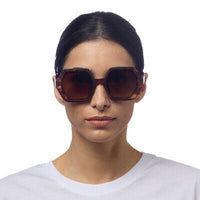 Mulher a usar óculos de sol OKKIA EMMA com armação tartaruga Classic Havana e lentes castanhas degradé polarizadas