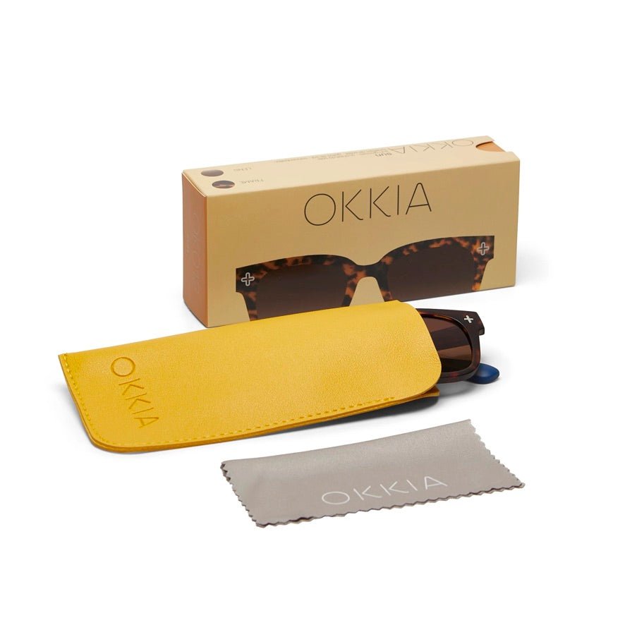 Óculos de sol OKKIA Giovanni com armação tartaruga e azul, estojo amarelo e pano de limpeza da marca GRINE