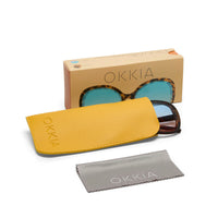Óculos de sol GRINE OKKIA Monica com armação redonda Havana, lentes degradé azul e rosa, bolsa amarela e pano limpeza