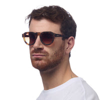 Homem a usar óculos de sol GRINE OKKIA ZENO com armação Classic Havana em acetato e lentes castanhas polarizadas
