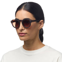 Mulher a usar óculos de sol GRINE OKKIA ZENO com armação Classic Havana e lentes castanhas polarizadas
