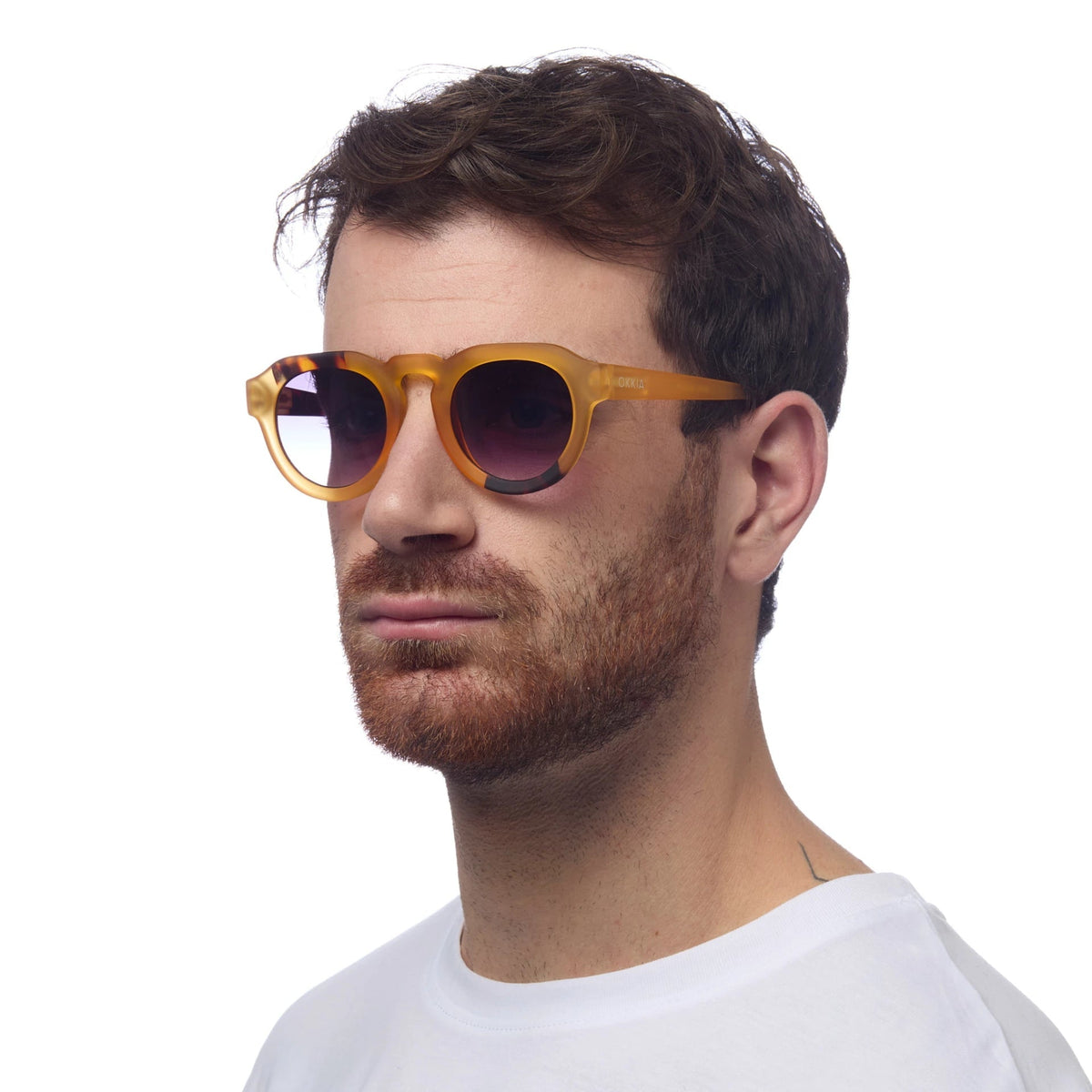 Homem a usar óculos de sol GRINE OKKIA ZENO com armação em acetato Yellow Havana e lentes pretas polarizadas.