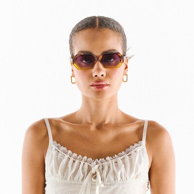 Modelo usa óculos de sol GRINE OKKIA ANDREA com armação em acetato Yellow Havana e lentes castanhas degradé.