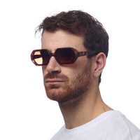 Homem a usar óculos de sol GRINE OKKIA ANDREA com armação em acetato havana e lentes castanhas degradé polarizadas.