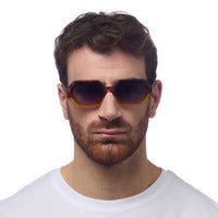 Homem a usar óculos de sol GRINE OKKIA ANDREA com armação em acetato amarelo e castanho e lentes degradé polarizadas