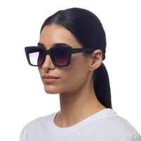 Mulher a usar óculos de sol GRINE OKKIA ELBA pretos com armação de acetato e lentes degradé polarizadas