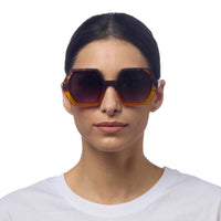 Modelo usa óculos de sol GRINE OKKIA EMMA com armação geométrica Havana Yellow e lentes pretas polarizadas
