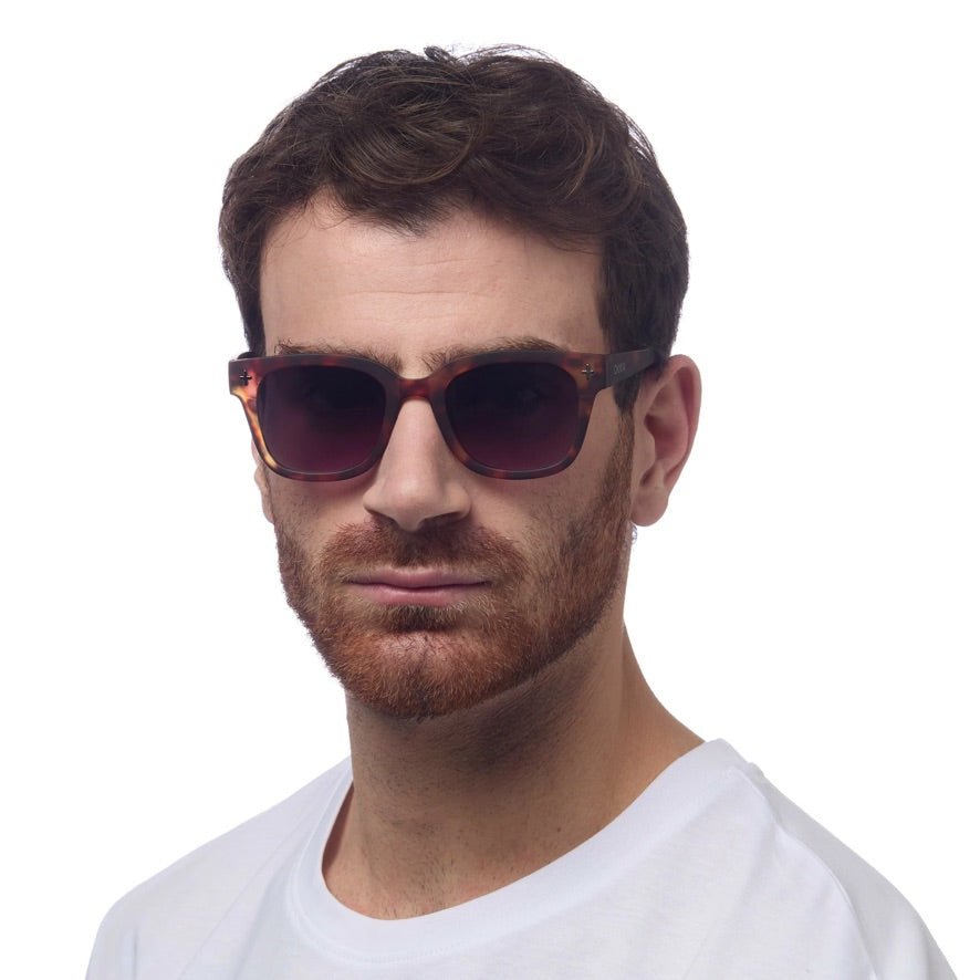 Homem a usar óculos de sol GRINE OKKIA Giovanni com armação tartaruga e azul e lentes castanhas polarizadas