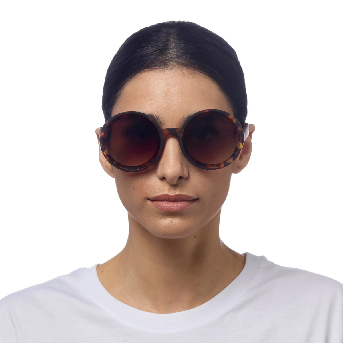 Mulher a usar óculos de sol redondos GRINE OKKIA Monica com armação tartaruga e lentes castanhas polarizadas