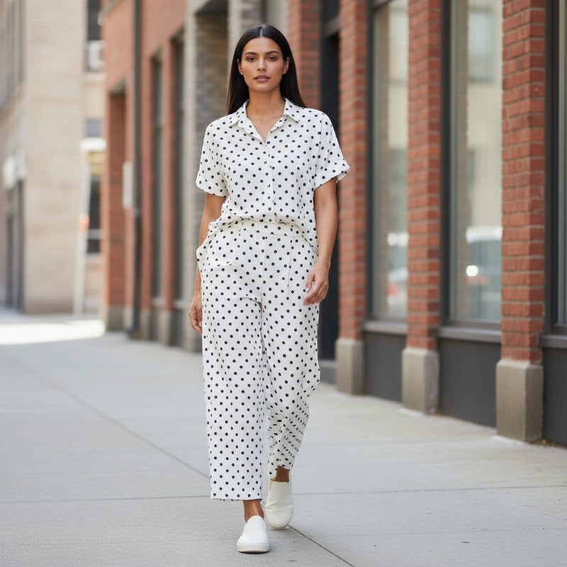 GRINE pearl white cotton short-sleeve shirt with black polka dots and side slits, paired with matching wide-leg trousers.