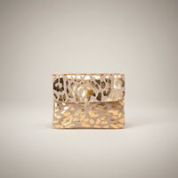 Porta-moedas GRINE em camurça bege com padrão animal print dourado e fecho de mola, design compacto e elegante.
