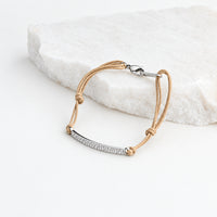 Pulseira GRINE ajustável em aço inoxidável prateado com detalhes brilhantes e cordão bege sobre pedra branca