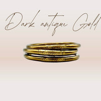 Pulseira GRINE artesanal budista em tom dourado antigo com conector de cobre gravado, símbolo de sorte e proteção.