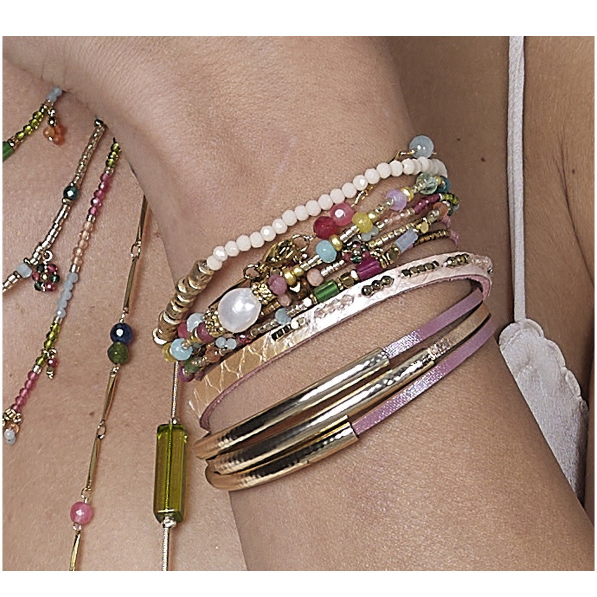 Pulseira Funky GRINE em pele sintética rosa e metal dourado com fecho magnético, usada em conjunto com outras peças.