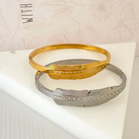 Pulseiras GRINE modelo Leaf em aço inoxidável dourado e prateado com detalhes em strass sobre suporte triangular
