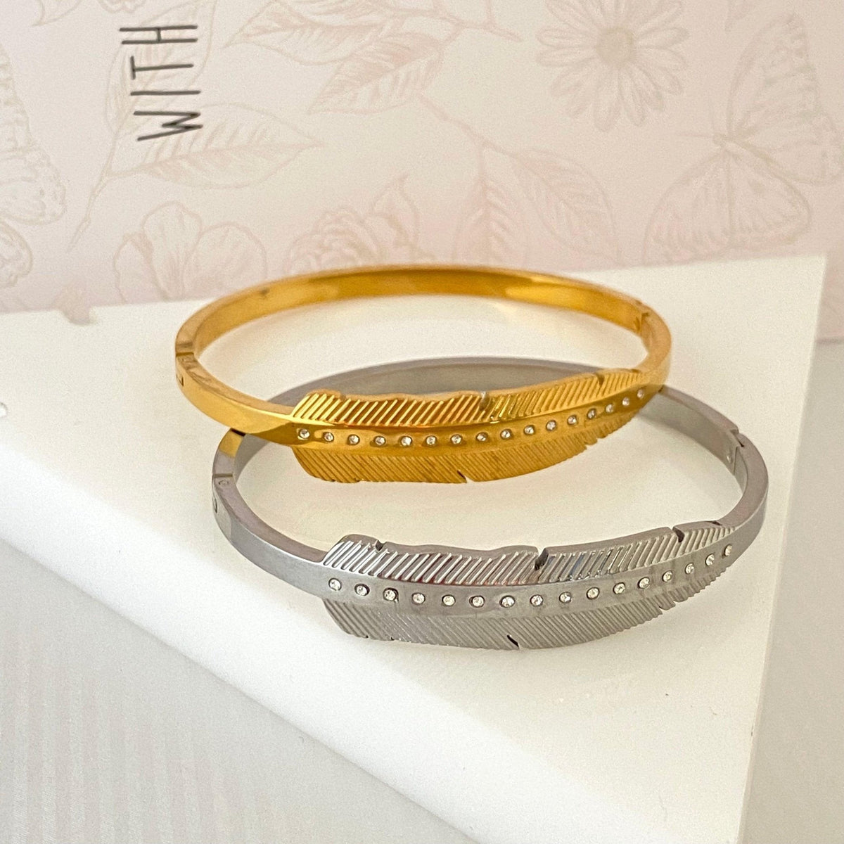 Pulseiras GRINE modelo Leaf em aço inoxidável dourado e prateado com detalhes em strass sobre suporte triangular
