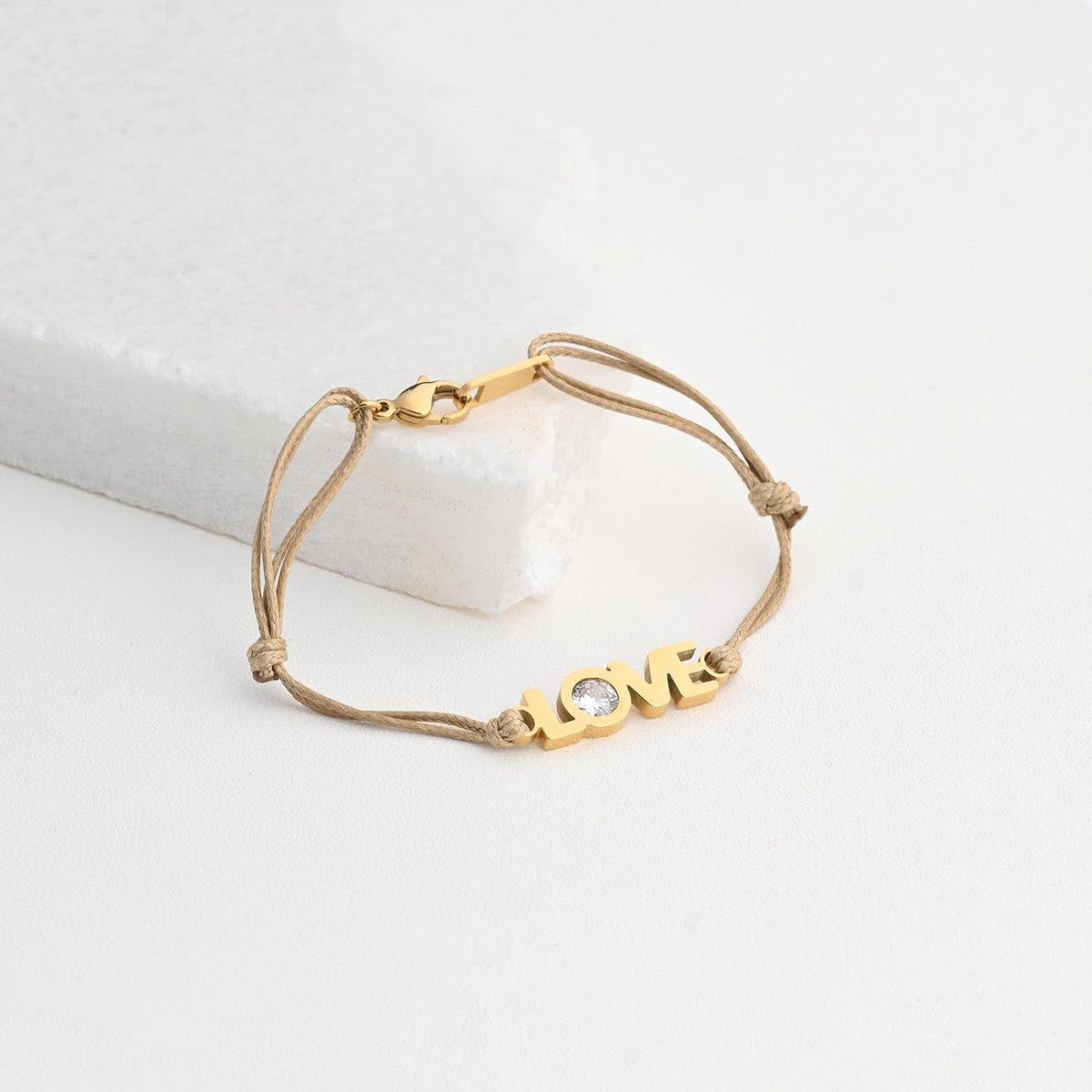 Pulseira GRINE LOVE em aço inoxidável bege com detalhe brilhante e fecho ajustável sobre base branca